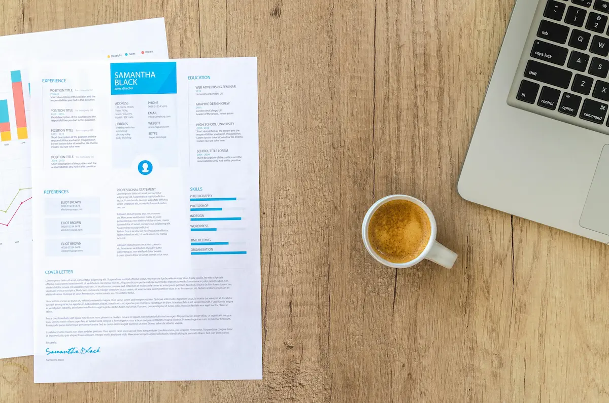 Top view of a desk with resume, coffee cup, and laptop on a wooden surface, ideal for business concepts. Top view of a desk with resume, coffee cup, and laptop on a wooden surface, ideal for business concepts.