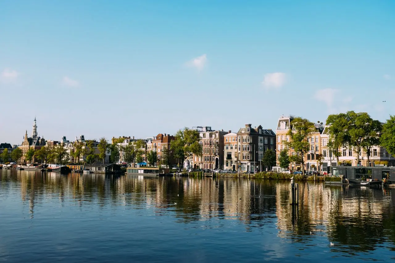 Picturesque view of Amsterdam's canals and historic buildings under a clear blue sky. Picturesque view of Amsterdam’s canals and historic buildings under a clear blue sky.