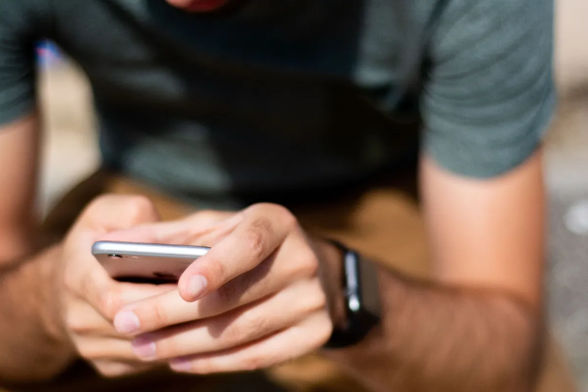 Close-up of hands using smartphone outdoors, depicting modern mobile communication. Close-up of hands using smartphone outdoors, depicting modern mobile communication.