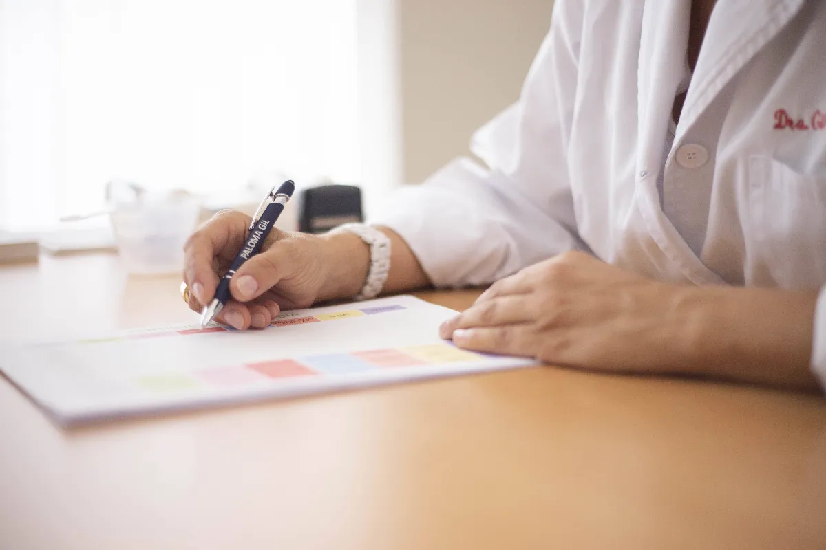 Close-up of a female doctor writing a prescription at a desk in an office setting. Close-up of a female doctor writing a prescription at a desk in an office setting.